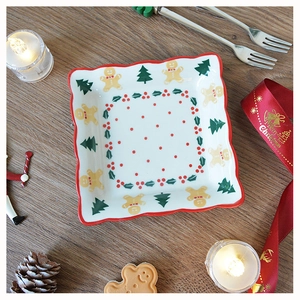 Top view of square ceramic Christmas plate with gingerbread man pattern on wooden table