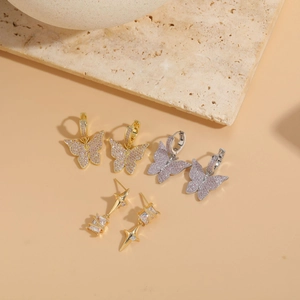 Close-up of butterfly and star earrings with pink zircon in gold and silver plating