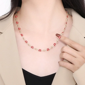 Elegant gold chain necklace with red flower pendant worn by model in a close-up shot