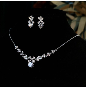 Detailed view of silver flower necklace and earring set with white zircons on a neck bust