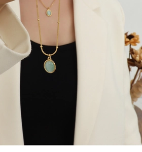 Close-up of a 18k gold plated stainless steel necklace with green cat-eye stone pendant
