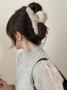 Gros plan d'une pince à cheveux en fourrure de vison marron clair sur un chignon élégant