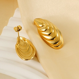 Detailed close-up of 18k gold wavy shell-shaped earrings on elegant silk fabric background