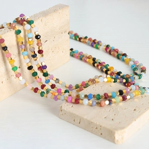 Handmade necklace with multi-colored faceted beads and golden metal geometric spacers