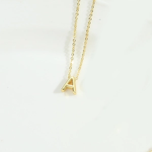 Detailed close-up of a minimalist golden letter A pendant on a fine clavicle chain
