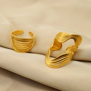 Set of two irregular 18K gold plated minimalist rings on a beige silk background