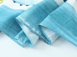 Detailed view of lemon print poplin fabric showing texture and blue watercolor patterns