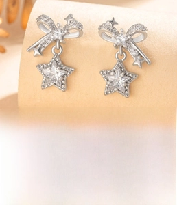 Detail of silver bow and star earring made of titanium steel with sparkling zircon stones
