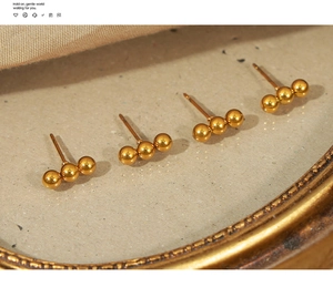 Detail of four-piece gold plated stainless steel stud earrings with triple ball design