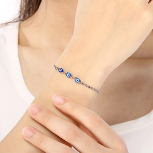 Detailed view of silver evil eye bracelet with three blue charms on model wrist