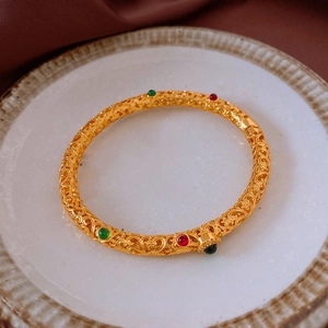 Macro view of a 24K gold plated filigree bangle featuring colorful gemstone inlays