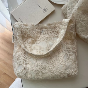 Detail of vintage floral lace embroidery and fabric label on a beige cotton shoulder bag