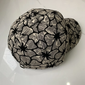 Close-up of baseball cap featuring intricate floral lace texture and metal back buckle