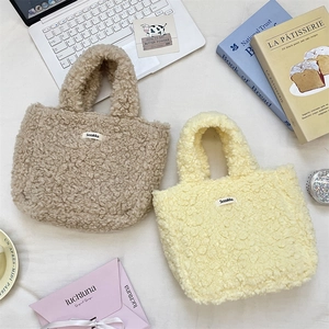 Close-up of soft plush lamb wool handbags in oat and pale yellow with woven labels