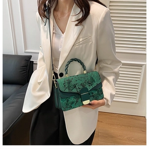 Détail du sac à main vert foncé avec broderie florale vintage et poignée tressée