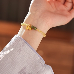 Detail eines Armbands aus gelben Bergkristallperlen mit goldenem Kalebasse-Anhänger