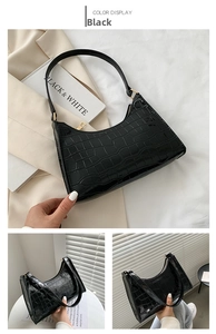 Detail of black faux crocodile skin texture and gold hardware on minimalist baguette bag