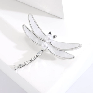 Macro shot of silver dragonfly brooch featuring mother-of-pearl wings and pearl head details