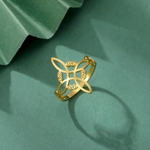 Gold plated stainless steel Celtic knot ring with hollow geometric pattern on green fabric