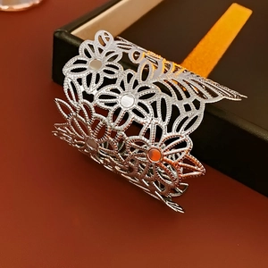 Macro shot of silver wide openwork floral cuff bracelet with intricate metal flower patterns