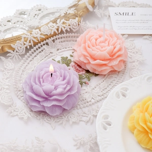 Peony shaped scented candles in pink, purple, and yellow on lace fabric decoration