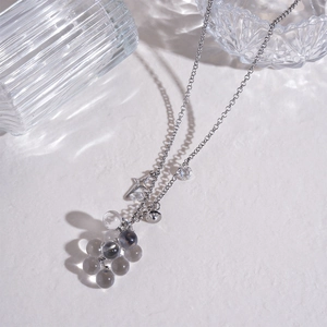 Detail shot of silver star and grape-shaped glass bead necklace on white texture