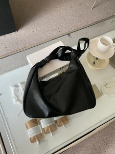 Vintage black PU leather crescent tote bag on a modern glass table in a lifestyle setting