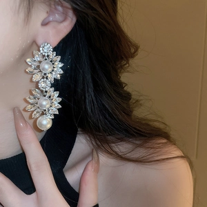 Close-up of floral tassel earrings with sparkling crystals and white pearls on a model