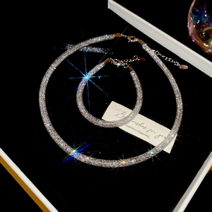 Macro shot of silver-toned mesh tube necklaces with sparkling crystals on black velvet