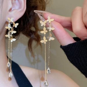 Detailed view of long gold butterfly tassel earrings with crystal drops worn by a model