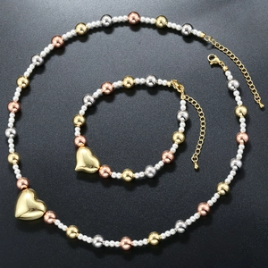 Detail of pearl jewelry set with tri-color metal beads and large golden heart pendant