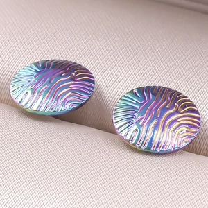 Macro shot of colorful rainbow stainless steel earrings with textured fingerprint pattern
