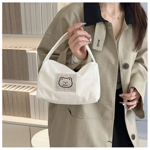 Detail of white corduroy mini tote bag with cute bear embroidery and text label