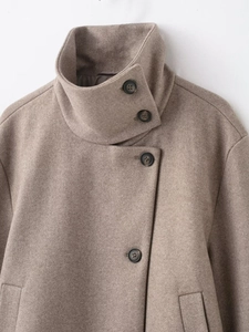 Dettaglio del collo alto e dei grandi bottoni sul cappotto di lana color cammello