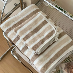 Detail of thick striped coral fleece bath towel with hanging loop on metal rack