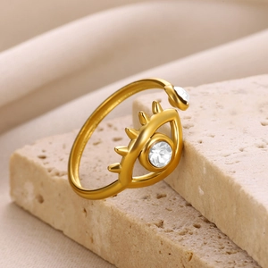 Macro detail of gold-tone evil eye ring with sparkling white zircon insets on stone base
