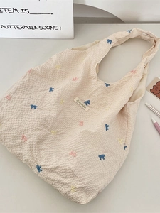 Sac fourre-tout beige gaufré avec nœuds brodés colorés et étiquette de marque