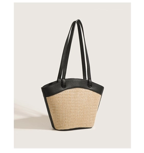 Detailed view of black leather handles and woven texture on a straw beach tote bag