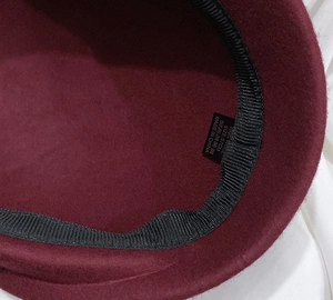 Detailed interior of wine red wool beret showing the 100% wool label and 57cm size tag