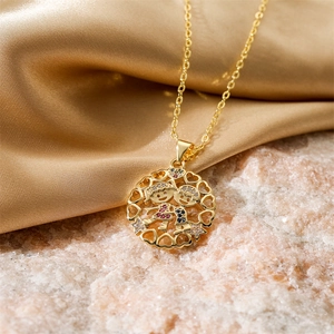 Macro detail of gold necklace pendant with boy and girl figures set with rhinestones