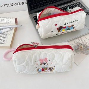Detail view of quilted fabric pencil cases with dog embroidery and red zipper closures