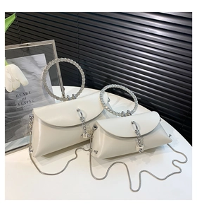Detail view of pearl white evening bags with rhinestone ring handles and silver chains