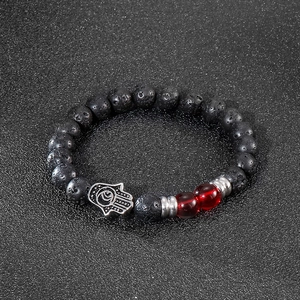 Detailed view of lava stone beads with red glass accents and a Hamsa palm pendant
