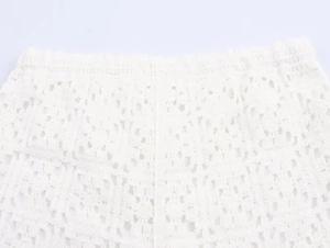 Detail of elastic waistband and intricate crochet lace texture on white knit shorts