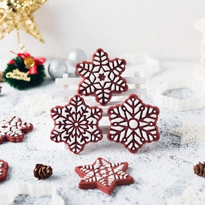 3D snowflake cookie cutters set for Christmas baking with red iced snowflake biscuits