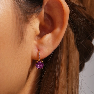 Detail of luxury S925 silver earring with purple round gemstone on model's ear