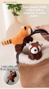 Close-up of plush red panda keychain with magnetic paws attached to a brown bag handle