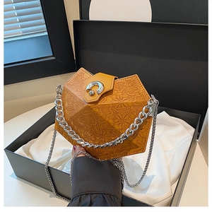 Detailed shot of a mustard yellow rhombic chain bag with silver clasp in a gift box