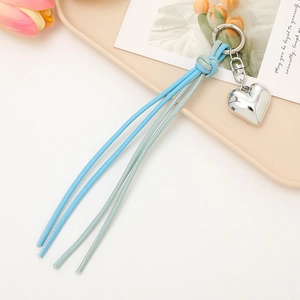 Close-up of blue and green braided leather keychain with silver heart-shaped pendant