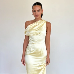 Detail of light yellow one-shoulder satin dress with elegant pleats and silky texture